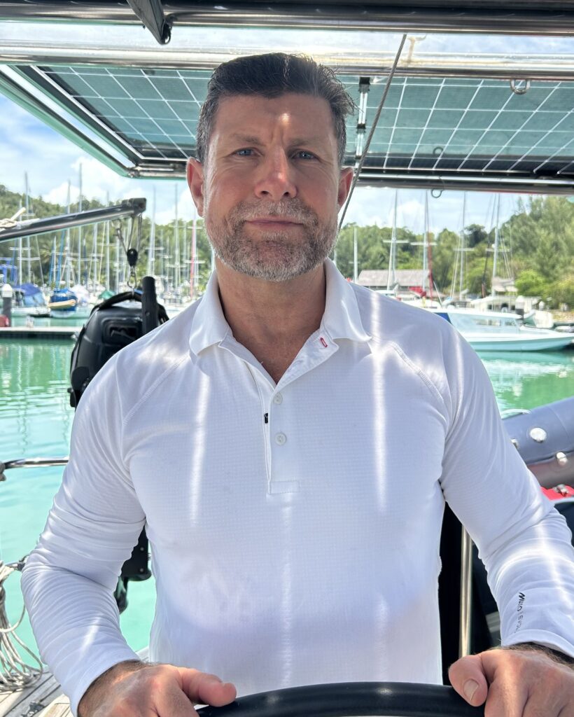 Dr Michael Player at a yacht's helm